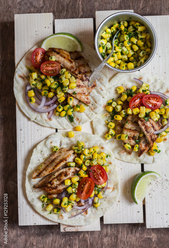 Grilled chicken and corn salsa tortilla on a wooden board. Top view, flat lay