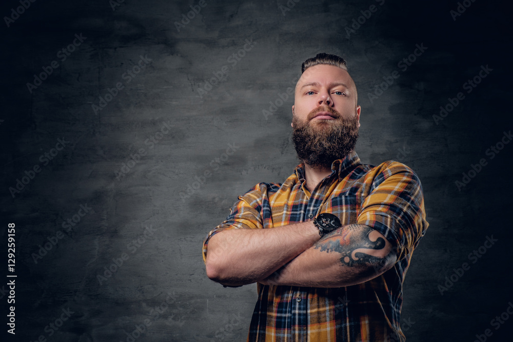 Bearded male with crossed arms, dressed in a yellow plaid shirt.