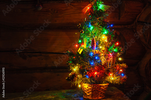 Small Christmas tree with multi colored lights at dark countryside room