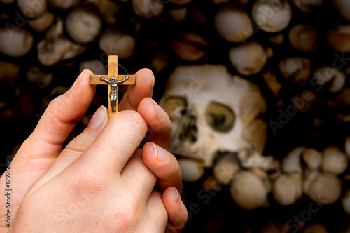 Female hands with cross on skulls and bones background