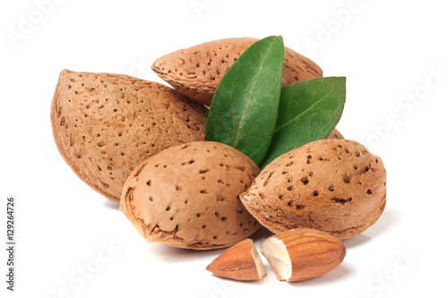 heap of almonds in their skins and peeled with leaf isolated on white background