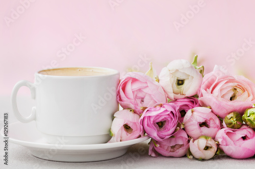 Beautiful spring Ranunculus flowers and cup of coffee on gray stone table. Pastel color. Greeting card for Valentines or Womans Day. Breakfast. Empty space for text.