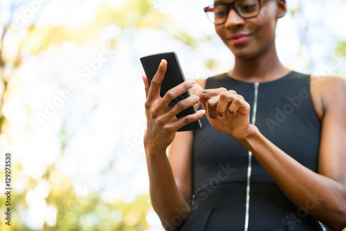 Young african businesswoman wearing glasses with the phone outside