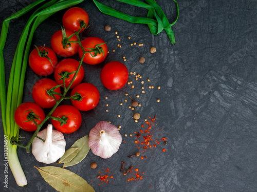 Fresh cherry tomatoes on black background with onion and garlic. Top view with copy space.