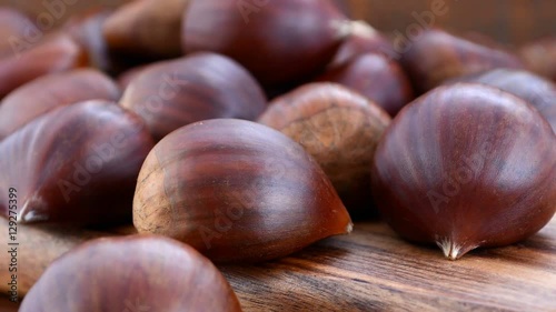 Close up macro of chestnuts on wooden table, panning right, HD real time.