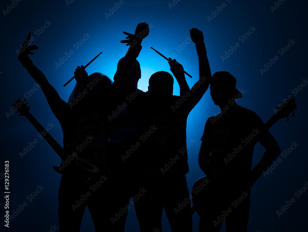 Band of young male musicians standing with instruments on a blue background