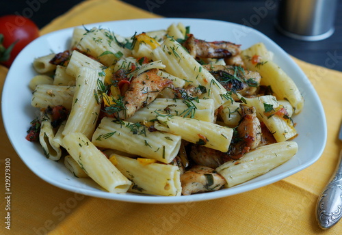 tortiglione pasta with chicken in a sauce of tomato, pepper and parsley on a yellow background  photo