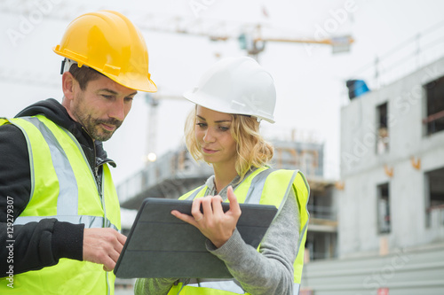 builders in hardhat with tablet at construction photo