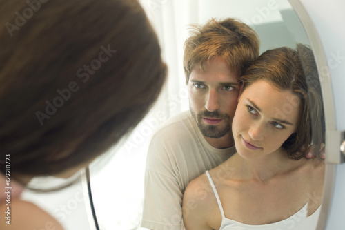 Couple cheek to cheek, looking at each other in mirror