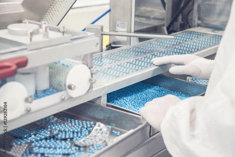 Technician operating prescription drug packaging equipment Technician operating prescription drug packaging equipment