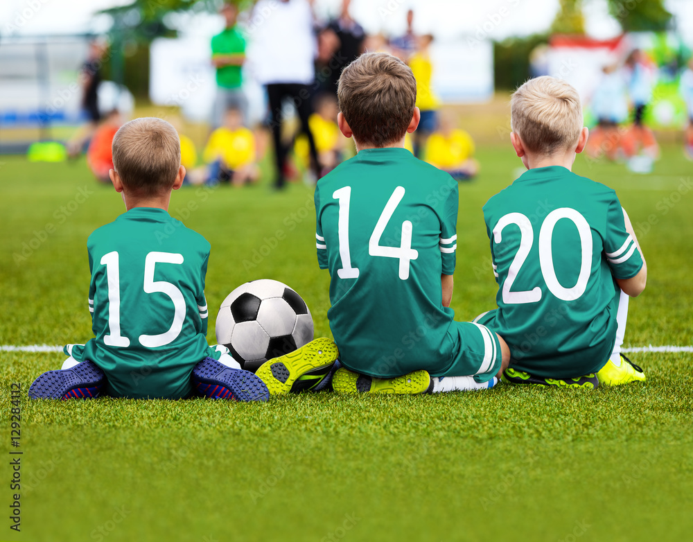 Children Soccer Team Playing Match. Football Game for Kids. Young Soccer Players Sitting on Pitch. Little Kids in Green Soccer Jersey Sportswear Children Soccer Team Playing Match. Football Game for Kids. Young Soccer Players Sitting on Pitch. Little Kids in Green Soccer Jersey Sportswear