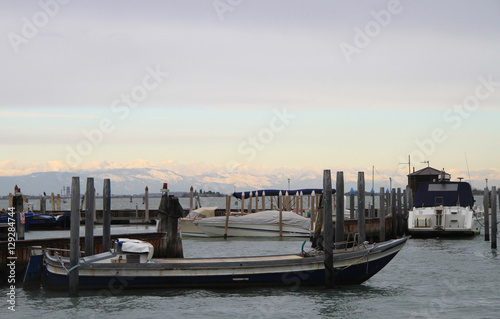 Moored gondolas and boats to the pier in Venice