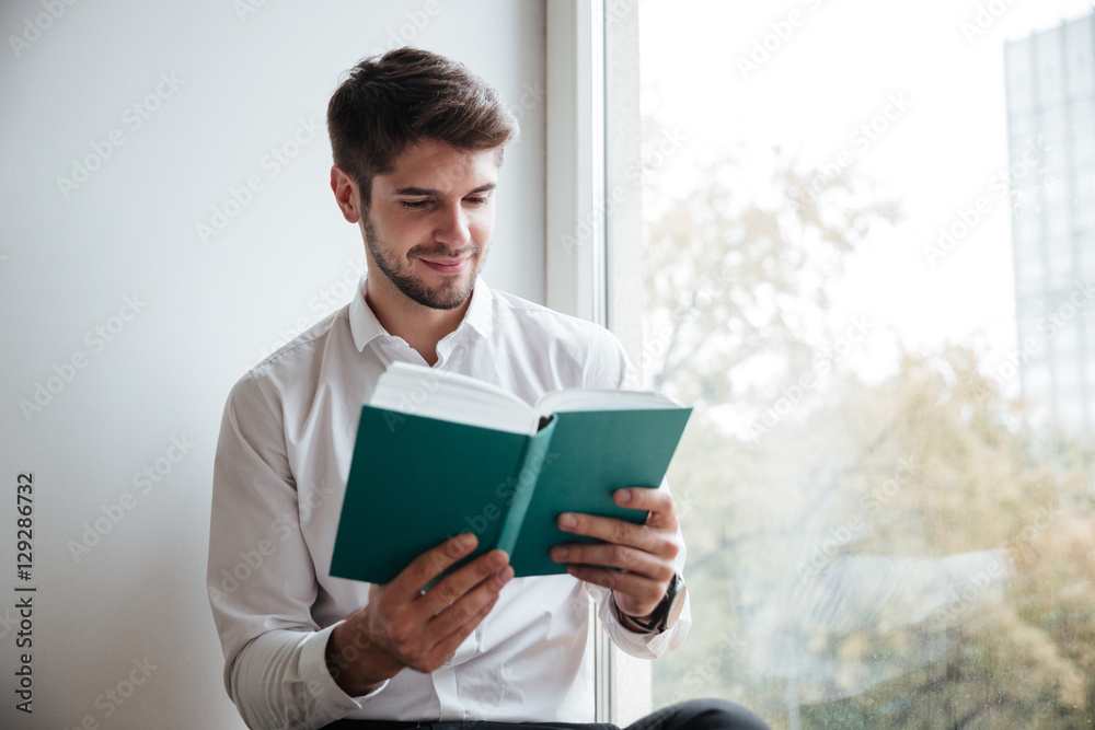 Cheerful businessman sitting in cafe and reading a book Cheerful businessman sitting in cafe and reading a book