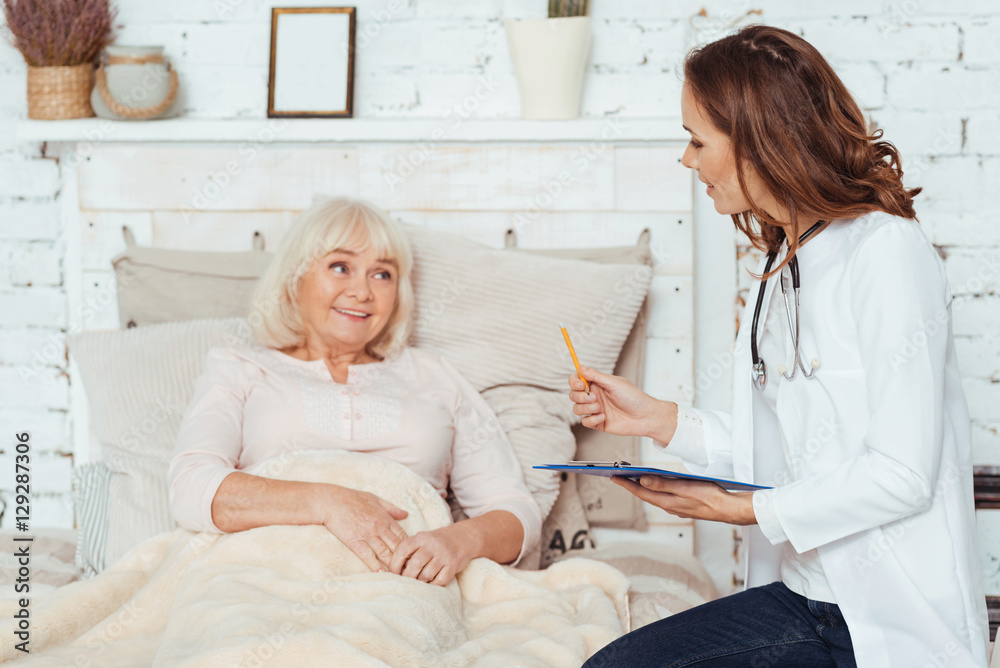 Professional positive female doctor examinig her patient at home