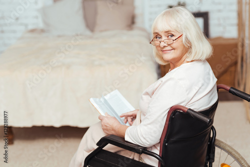 Pleasant disabled woman sittign in the wheelchair at home