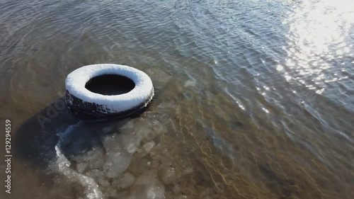 Old tire under snow in river sand in winter time. Steadicam shot.
