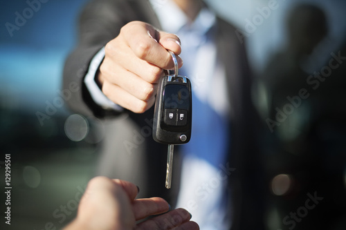 Male dealer hand giving car keys to female person