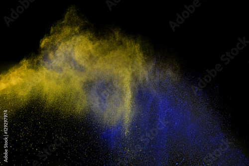 Blue and yellow powder explosion isolated on black background