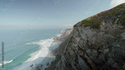 Slow motion shot of Cabo da Roca (Cape Roca), Portugal. The most westerly point of mainland Europe on a sunny summer or spring day. View of beautiful cliffs and rocks, Atlantic ocean waves. photo