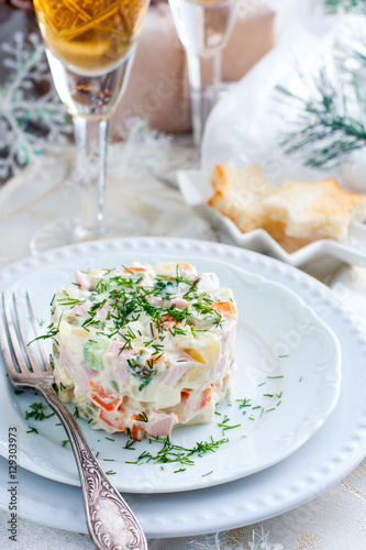 Traditional Russian Christmas Salad "Olivier" on a white plate in the Christmas decor