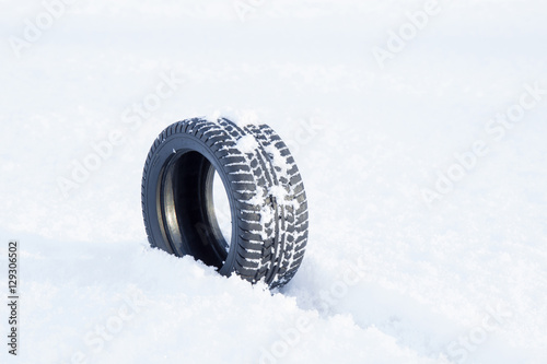 Black rubber tire rolling on the soft, fresh snow in the sunny day. White background. Seasonal tire change. © fotoduets