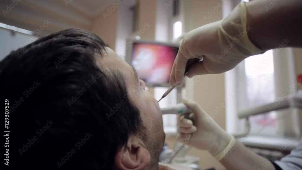 Dentist examining the mouth of a patient with an intraoral camera.