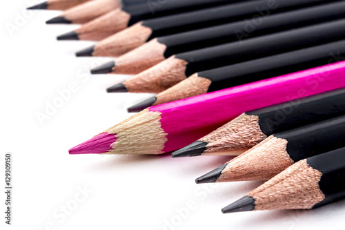 Red colored pencil jutting in row of black pencils, on white background