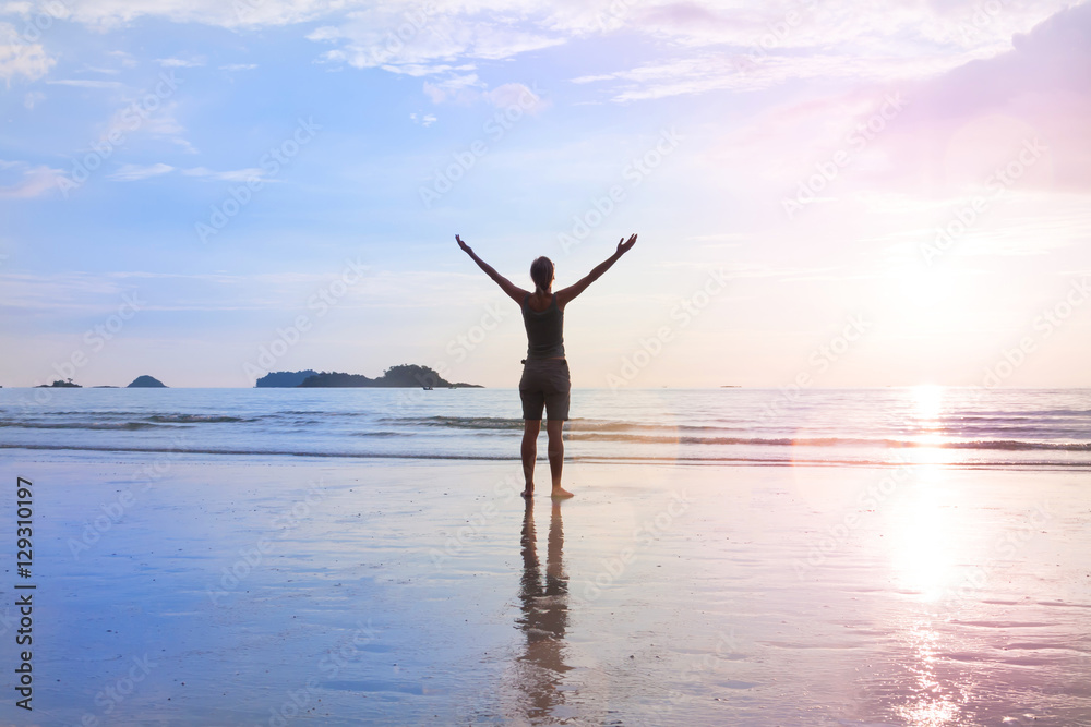 Young woman is standing at sea beach with hands to the side. Nature unity or success concept. Young woman is standing at sea beach with hands to the side. Nature unity or success concept.