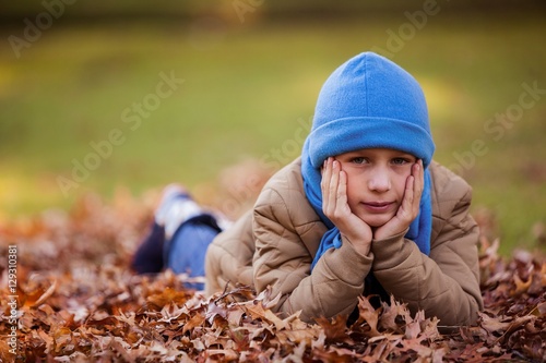 Portrait of cute boy lying at park during autumn