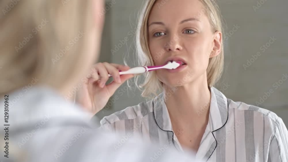 Pretty woman looking in the mirror and brushing her teeth properly Pretty woman looking in the mirror and brushing her teeth properly