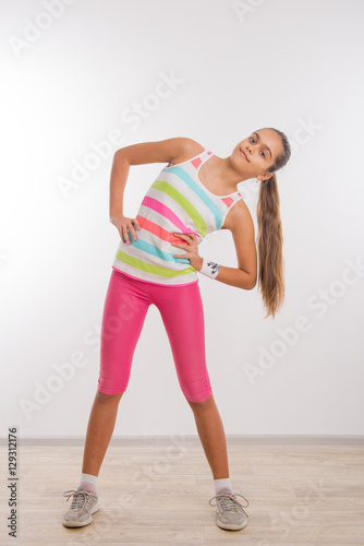 Physical training. Lovely little child is busy doing physical exercises. teen girl doing physical workout, bend of the trunk 