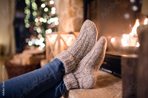 Quadro su tela Feet of unrecognizable woman in socks by the Christmas fireplace