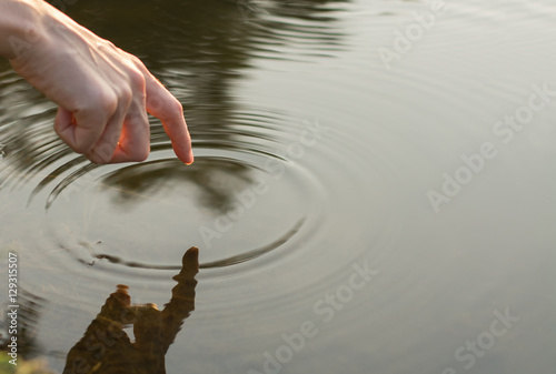 Close up finger touches water and drop of water falling and creating natural and calm waves,calmly concept,