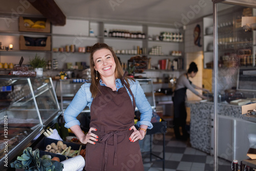 Portrait of smiling woman standing with hands on hip at store photo