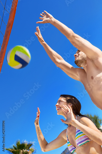 Smiling happy couple playing volleyball