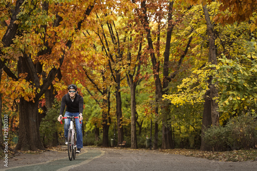 Man with his bike enjoying driving in park in autumn time, with