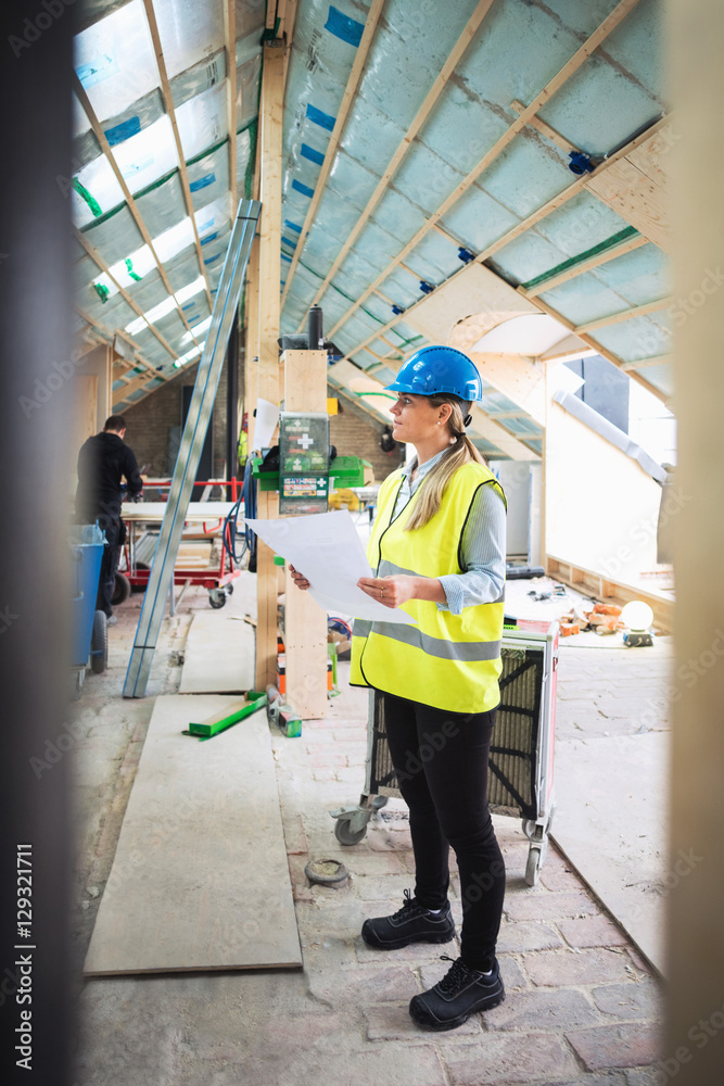 Confident female worker analyzing document while standing at construction site Confident female worker analyzing document while standing at construction site