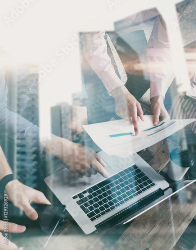 Double exposure of young coworkers working together on new startup project in modern office.Business people brainstorming concept.Skyscraper building at the blurred background.Vertical,flare effect.