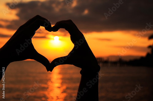 Sunset heart - capture of a silhouette heart shaped hands from a beach also there s a small pier on background 
