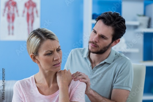 Physiotherapist massaging shoulder of a female patient