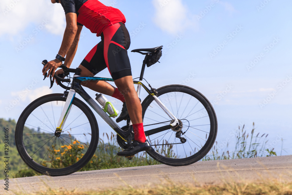 Man on a bicycle on a road between the beautiful mountains