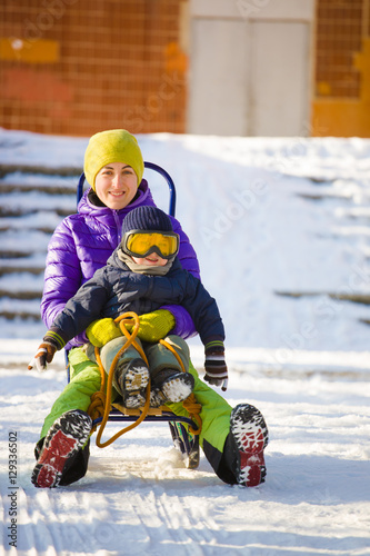 A mom with a child sledding.