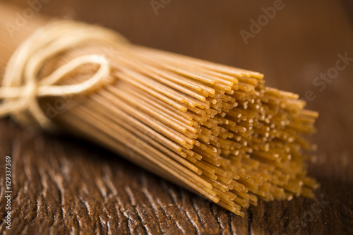 Tableau sur toile Yellow long spaghetti integral on a rustic background. Yellow it