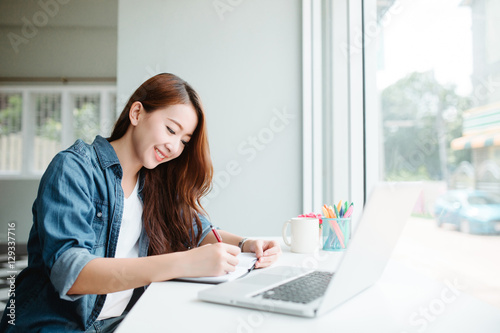 indoor picture of smiling Asia woman with notebook and pen
