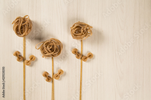 Whole-shaped integral pasta with flowers on a white wooden table