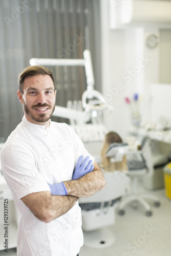 Young dentist posing in den...