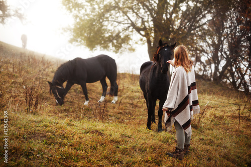 Woman with her horses. Concept about people and animals. Early morning. Misty mountain. Woman in boho style. © Serhii