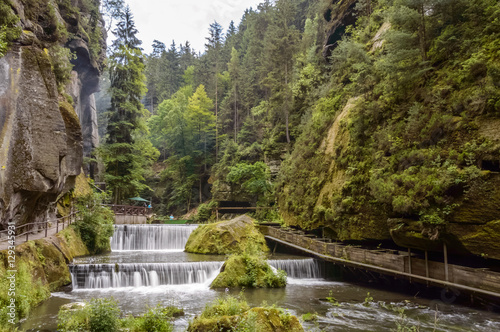 Foto Step waterfall surrounded by hilly forests
