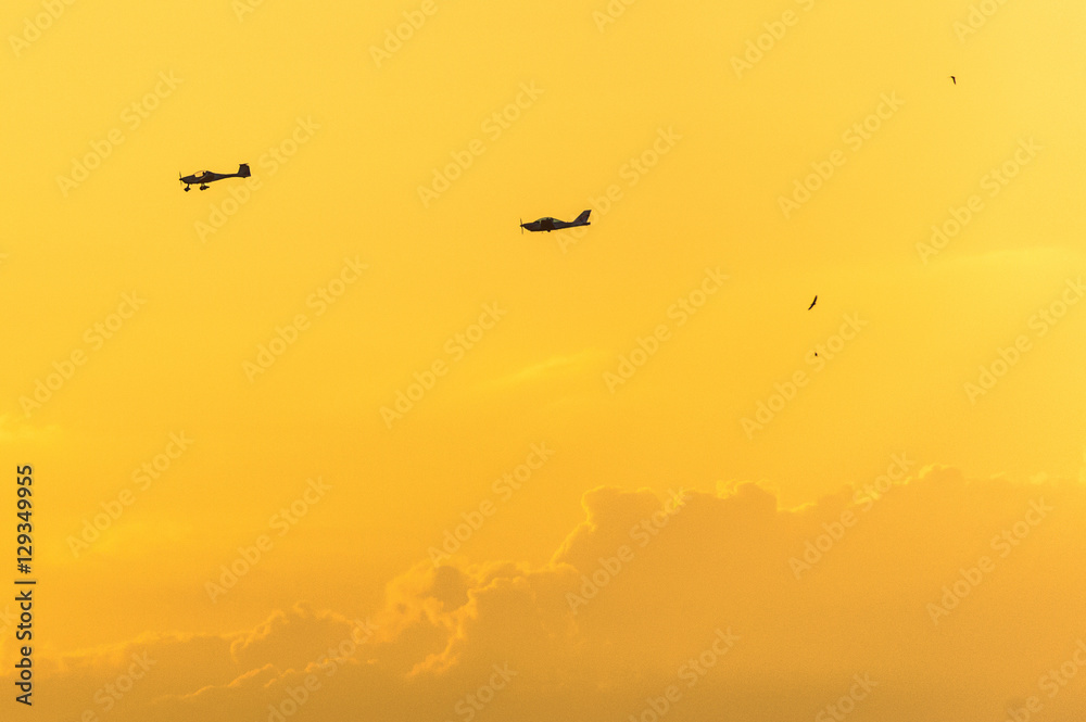 Two private planes in a yellowish orange sky