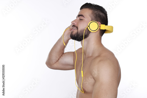 Sportlicher junger Mann mit nacktem Oberkörper hört Musik mit gelben Kopfhörern